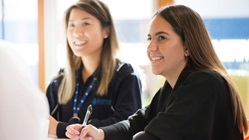 Two female graduates sitting at a meeting