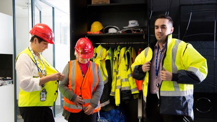 Three employees putting on PPE gear