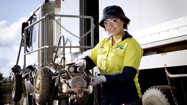 Employee wearing PPE standing by truck holding equipment