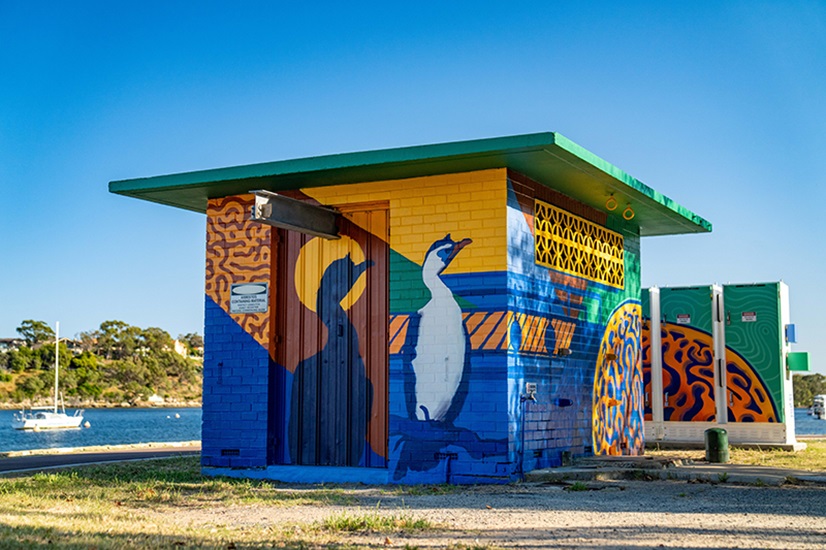 An operational asset is painted with a vivid yellow and blue mural featuring a bird