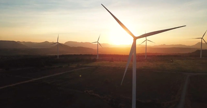 Multiple wind turbines pictured at sunset