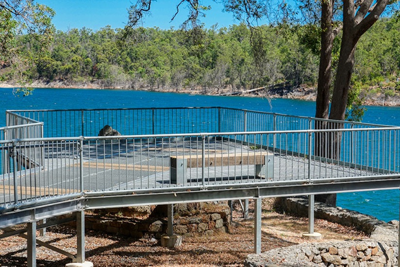 A gated viewing platform with benches looks out over the water at Mundaring Weir.