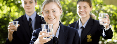 3 highschool students holding up glasses of water