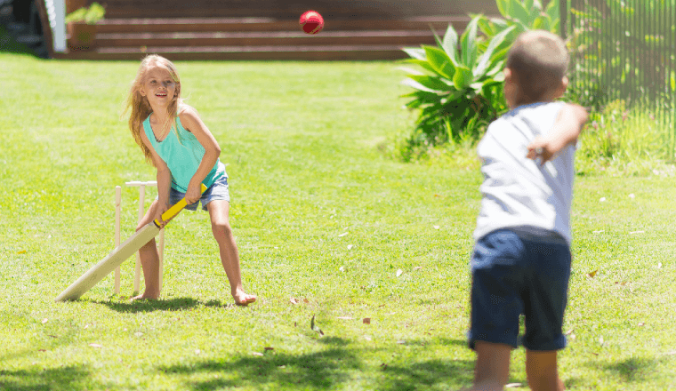 Girl and boy playing backyard cricket