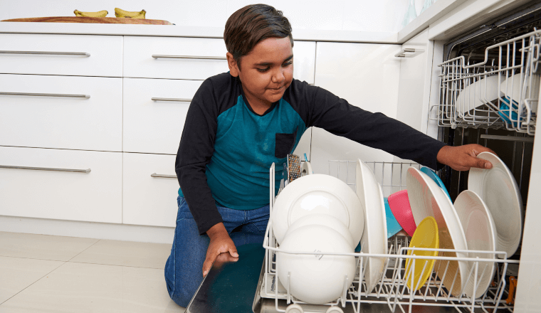 Boy loading dishwasher