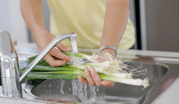 Washing veggies under a running tap in the kitchen
