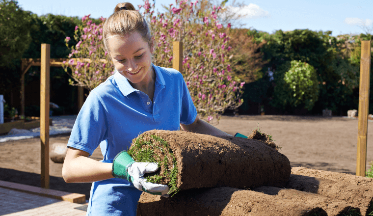 Female landscaper holding turf for new lawn