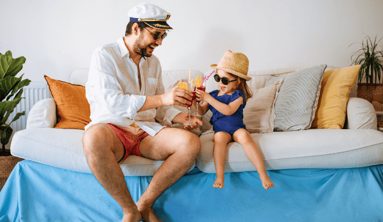 Dad with daughter on couch looking summery and toasting drinks