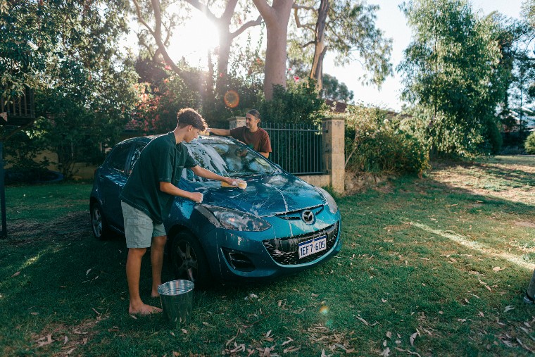 Father and son washing car on lawn