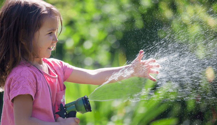 Young girl watering with a hose