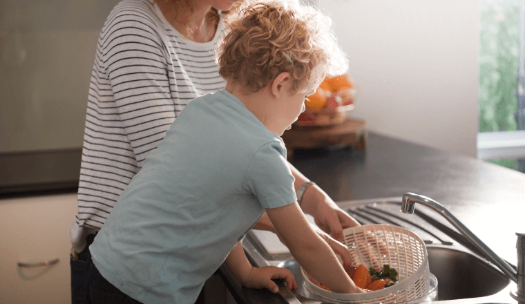 Boy washing vegetables at the kitchen sink