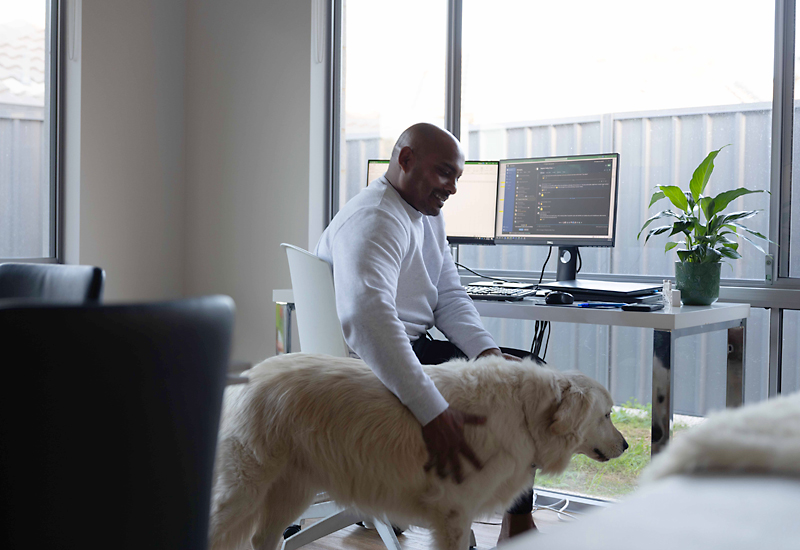 Image of employee working from home patting his dog