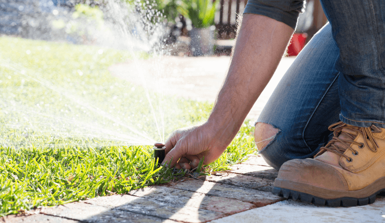 Man's hand adjusting a sprinkler