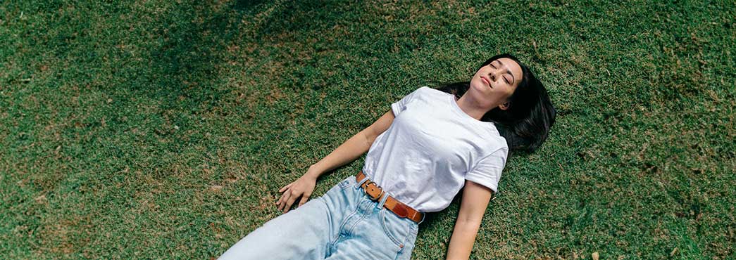 Person laying on their back on green grass